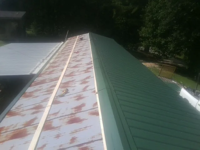 Old rusted panels beside newly installed green metal roofing — Wind Damage Roof Repair by Roofing Brothers in Grand Mound