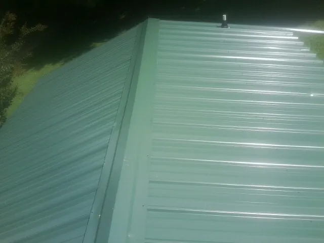 New green metal panels meeting at the ridge of a roof — Flat Roof Repair work by our crew in Grand Mound