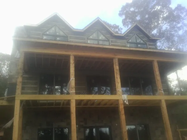 Dormers and porch framing on a large log home under construction — Roof Coating work by our crew in Grand Mound