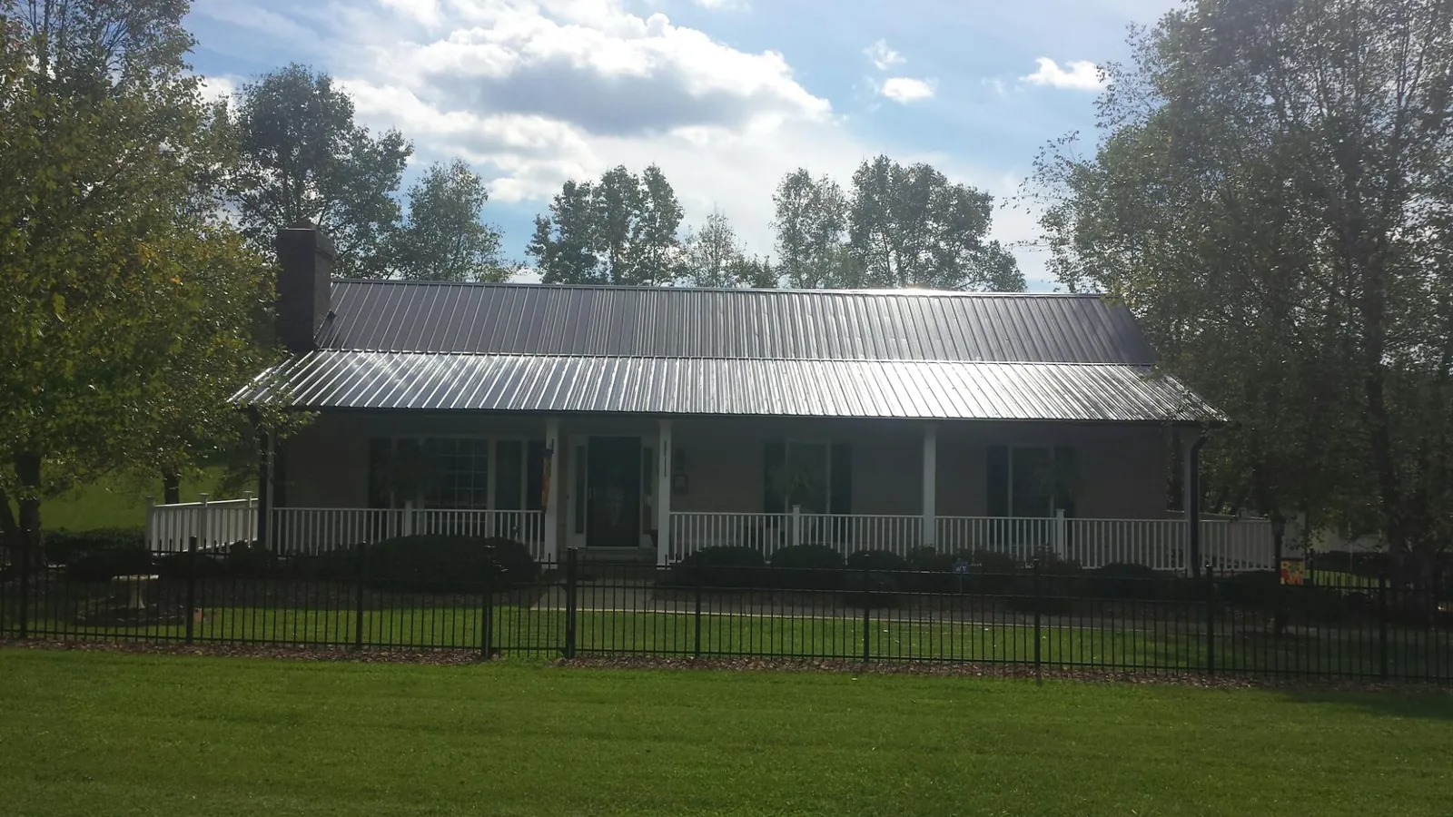 Gray metal roof on a brick ranch with a full width front porch — Gutter Guard Installation work by our crew in Grand Mound