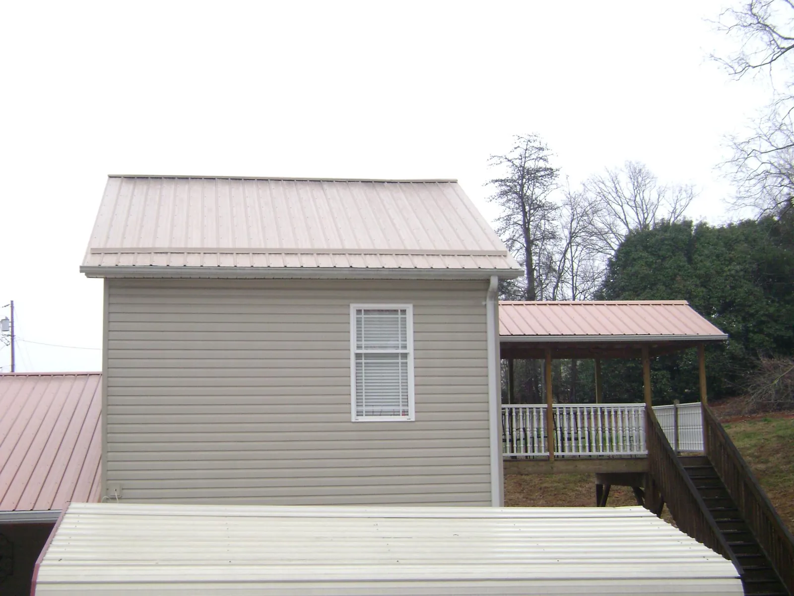 Tan metal roofs on a two story addition and attached porch, from a Roof Replacement job in Grand Mound