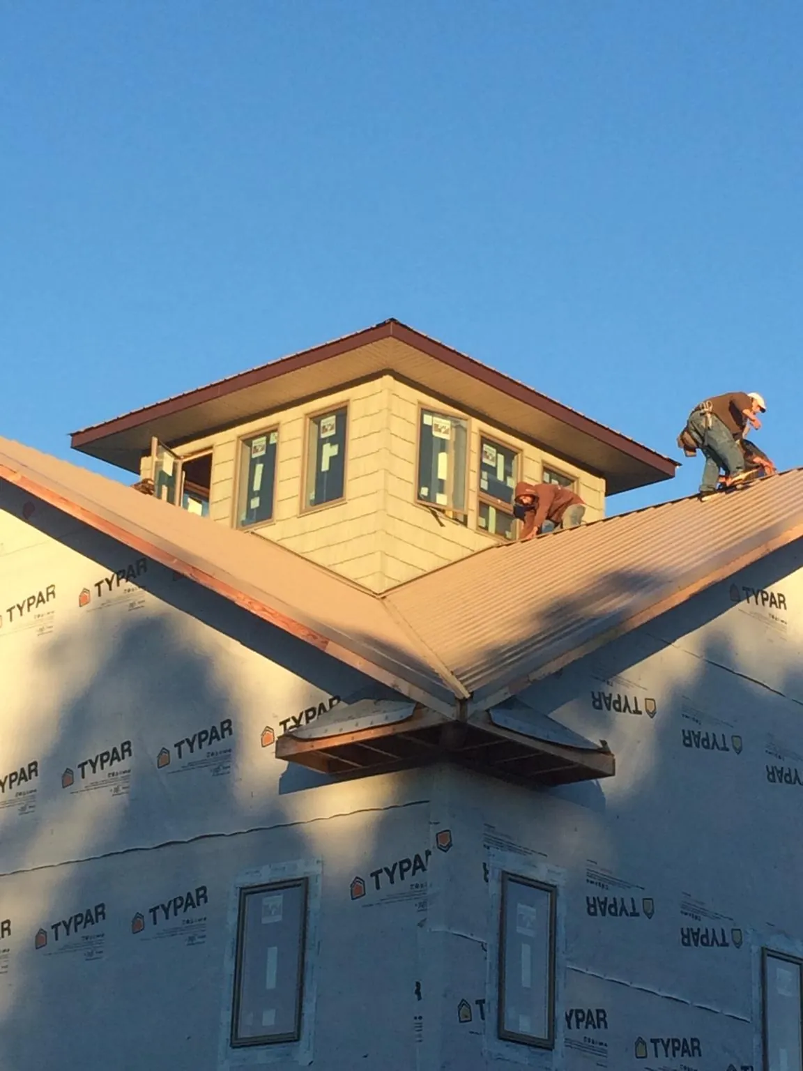 Roofers working around a rooftop cupola on a new metal roof at sunset — Roof Waterproofing in Grand Mound by Roofing Brothers